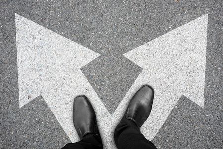 Businessman in black shoes standing at the crossroad making decision which way to go. Decision making concept.の写真素材