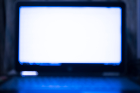 Abstract blur laptop computer on table and blue light shining from the screen for background.の写真素材
