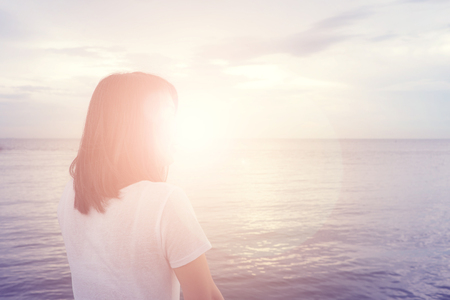 Woman standing on the balcony watching sunset on the horizon of the sea.の写真素材