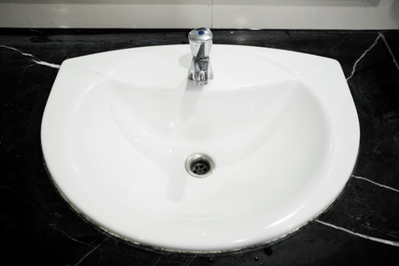 White ceramic sink and staniless steel faucet on black marble stand as barhroom and toilet...