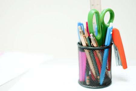 Holder basket and office supplies and white papers on working table. Work, education and back to...