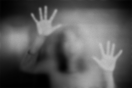 Shadow of woman on the frosted glass representing dangerous, fear, help, haunting, horror and scary.の写真素材