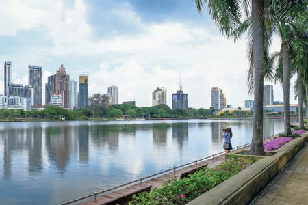 Female photographer taking photos of downtown bangkok across the lake, Thailand.のeditorial素材