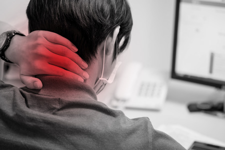Man put his hand on the back of his neck and feeling pain after working with computer for a long time. Office syndrome. Herniated disc.の写真素材