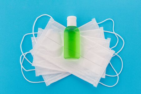 Top view of several medical surgical masks and sanitizer or antiseptic. Doctor's disposable respirator group with antibacterial agent. Isolated on a blue backgroundの写真素材