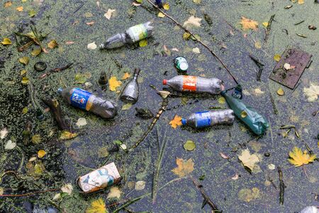 Plastic bottles, cans, and bags float in dirty, muddy water. Damaging the planet's ecology with...
