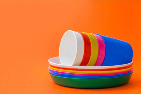 Children's unbreakable multicolored dishes, serving for a children's holiday. Isolated on an orange backgroundの写真素材
