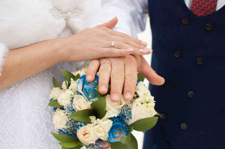 Hands of the bride and groom with rings, folded on a bouquet. Wedding concept