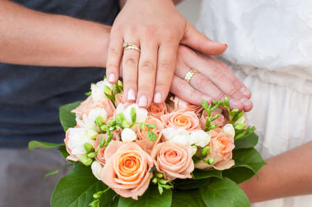 Hands of the bride and groom with rings, folded on a bouquet. Wedding conceptの写真素材