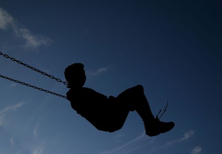 Child swinging in silhouetteの写真素材