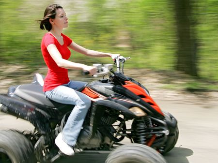 young adult female riding a 4 wheeler on a dirt road with good panning motion blurの写真素材