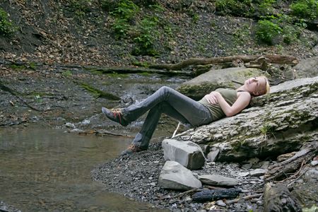 a beautiful caucasian woman laying on a large rock