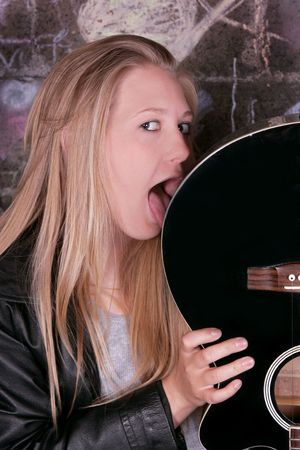 young moody adult female rocker licking her guitarの写真素材