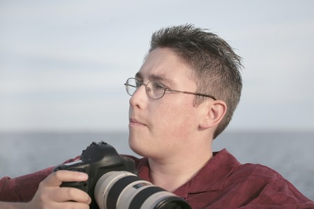 portrait of a man with his camera ready to take photos outdoors against the water