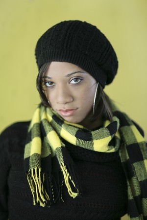 one fashionable young woman model posing over a yellow wall in cold weather garbの写真素材