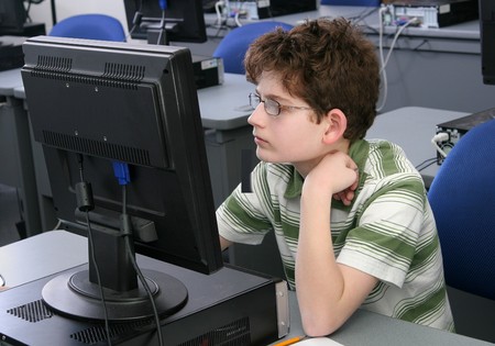 one young student boy studying on the computer in school