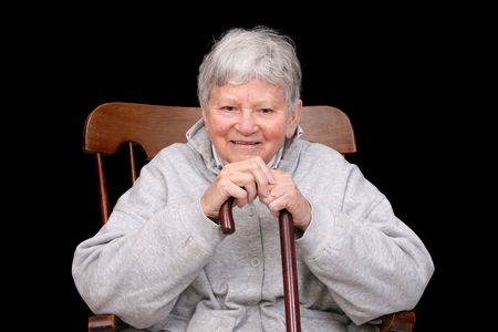 one elderly adult female sitting in a rocking chair holding her caneの写真素材