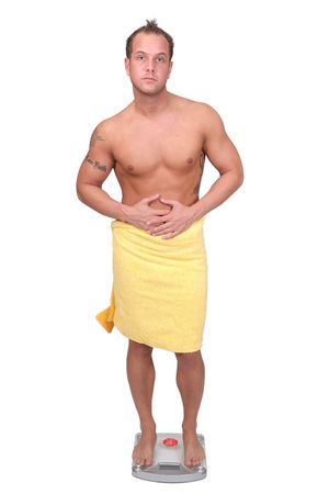 one adult man in a towel standing on the scale weighing himselfの写真素材