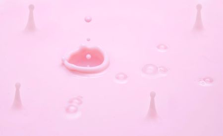 many drops and big hole in pink milk closeup with bubblesの写真素材