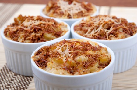 four ramekin bowls of homemade macaroni and cheese dinner topped with brown toasted cheesy crustの写真素材