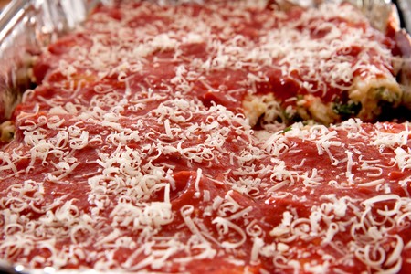 full tray of manicotti pasta topped with cheese ready to cook in a tin pan の写真素材