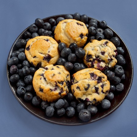 big plate of blueberry muffins surrounded by blueberries on blueの写真素材