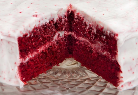 red velvet cake with one slice removed on a glass platter