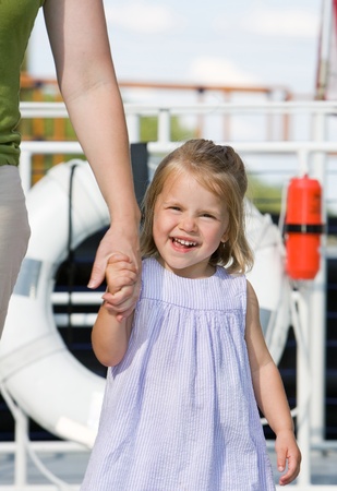 one young girl holding her mom's hand while walking on a cruise shipの写真素材
