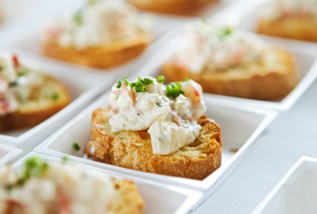 closeup of small seafood bruschetta appetizers in small white serving platesの写真素材