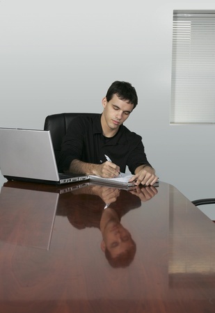 twenties guy writing at a conference table in an officeの写真素材