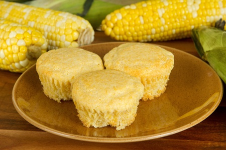 three fresh corn muffins with ingredients on a homestyle plateの写真素材