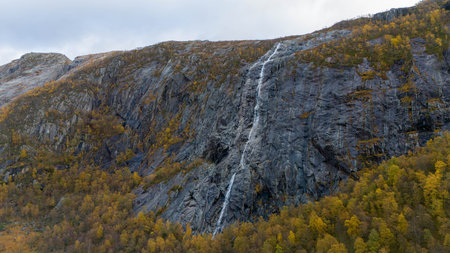 Waterfall Cascading Down Rocky Cliff in Autumn