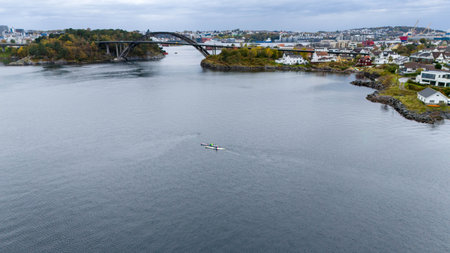 Aerial view of a serene coastal area with a bridge, houses, and kayakers.