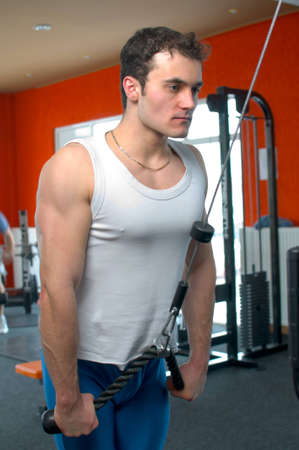 Man at the gym pulling weights on the windlass for working the triceps