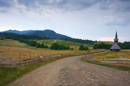 Beautiful scenery at evening from a countryside land with country road and a small old church.