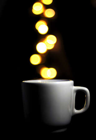 cup of coffee on black background, balls of light fall into coffee bokhesの写真素材