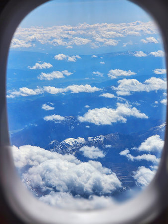 The Alps mountains with snow on top seen from the window of a plane mid-flight. Austria, Europe
