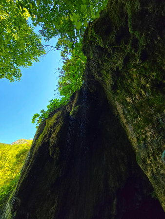 Moss rocks at Sipote Waterfall in a bright green forest with Bedeleu Mountain in background on a...