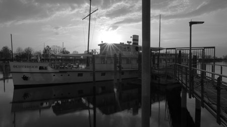 Sun rays over Historic ship Austria in Bregenz on Lake Constance with reflections in water in black and whiteの写真素材