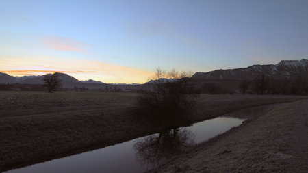 River in which a bare tree is reflected on a winter morning in the countryside in Austriaの写真素材