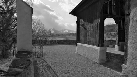 Entrance to the old St. Michael church in Feldkirch Tisis with mountains and clouds in the background in black and whiteの写真素材
