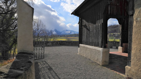 Entrance with iron gate to the old St. Michael church in Feldkirch Tisis with mountains and clouds in the backgroundの写真素材