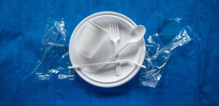 Some pieces of a disposable white plastic crockery in a blue background