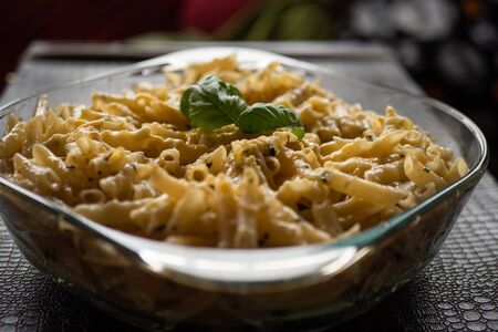 Macaroni with green pesto in a glass bowl