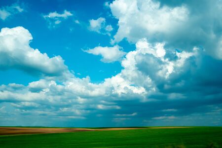 Cloudy blue sky over green horizonの写真素材