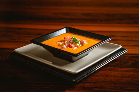 Typical spanish recipe for cordovan salmorejo in a square plate over a dark wooden table.の写真素材