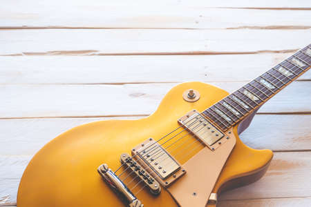 Beautiful classic golden electric guitar on a white wooden table, with copy space.