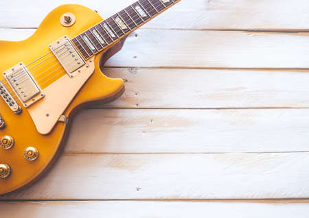 Beautiful classic golden electric guitar on a white wooden table, with copy space.の写真素材