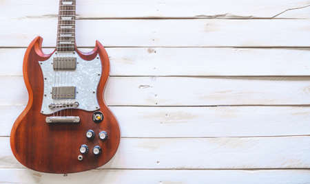 Classic red and white electric guitar on a white wooden table, with copy space.の写真素材