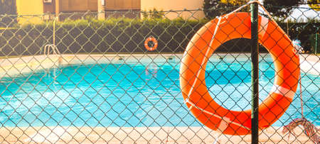 View of a salt water pool from the fence with an orange life float on a sunny summer day.の写真素材
